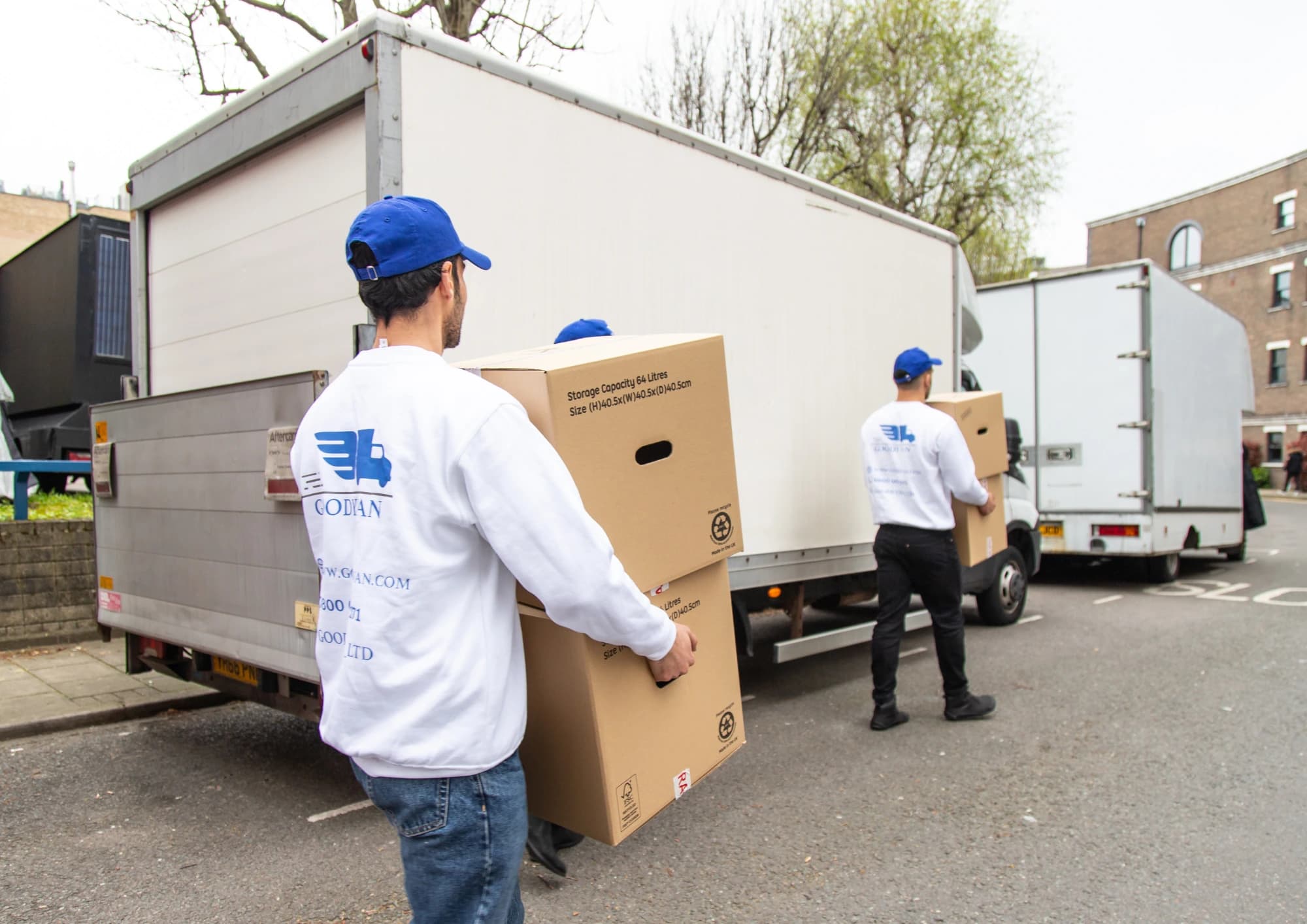 GoodyVan crew carrying boxed items beside delivery vans in London